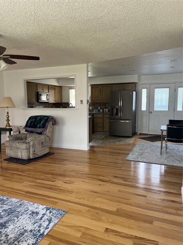 403 S Cherry St, Townsend, MT 59644 - living room featuring a ceiling fan, a textured ceiling, light wood-type flooring, plenty of natural light, and baseboards
