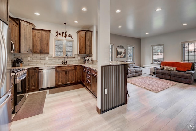 5235 Creekside Ln, Helena, MT 59601 - kitchen featuring stainless steel appliances, a sink, open floor plan, light stone countertops, and light wood-type flooring