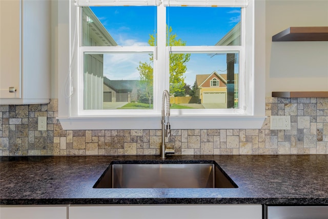 kitchen view of a sink, white cabinets, and decorative backsplash