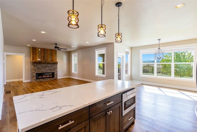 kitchen featuring open floor plan, stainless steel microwave, healthy amount of natural light, wood finished floors, and recessed lighting