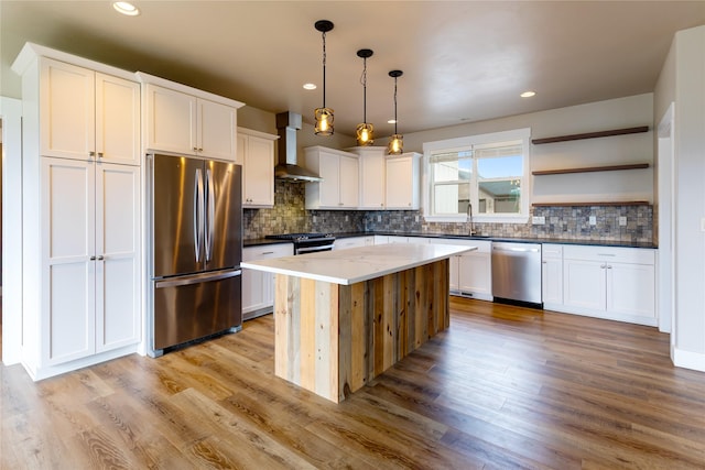 kitchen featuring stainless steel appliances, wall chimney exhaust hood, light wood finished floors, decorative backsplash, and recessed lighting