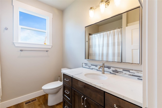 bathroom with wood finished floors, baseboards, vanity, and toilet