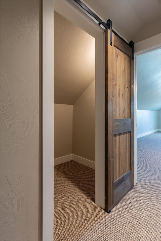 bonus room featuring carpet, vaulted ceiling, a barn door, and baseboards