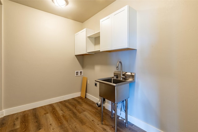 washroom featuring cabinet space, electric dryer hookup, hookup for a washing machine, wood finished floors, and baseboards