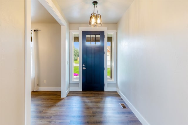entrance foyer with dark wood-style floors, baseboards, and a chandelier