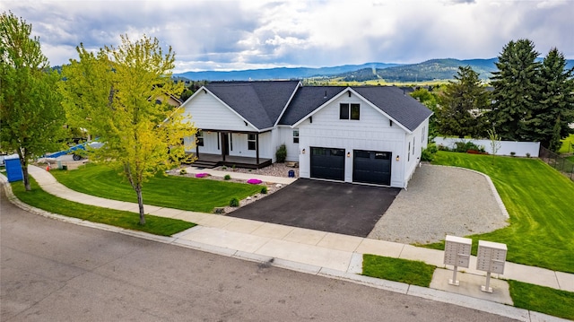modern inspired farmhouse with board and batten siding, a mountain view, asphalt driveway, covered porch, and a garage