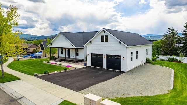 modern farmhouse featuring board and batten siding, a porch, a mountain view, and a front lawn