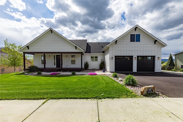 modern farmhouse style home featuring board and batten siding, a garage, a front lawn, asphalt driveway, and covered porch
