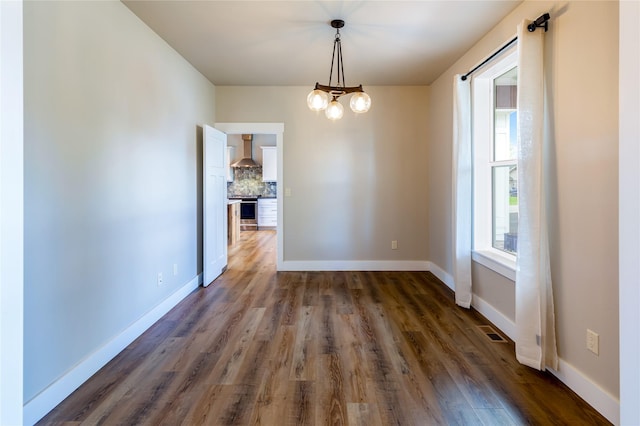 spare room with wood finished floors, a chandelier, and baseboards