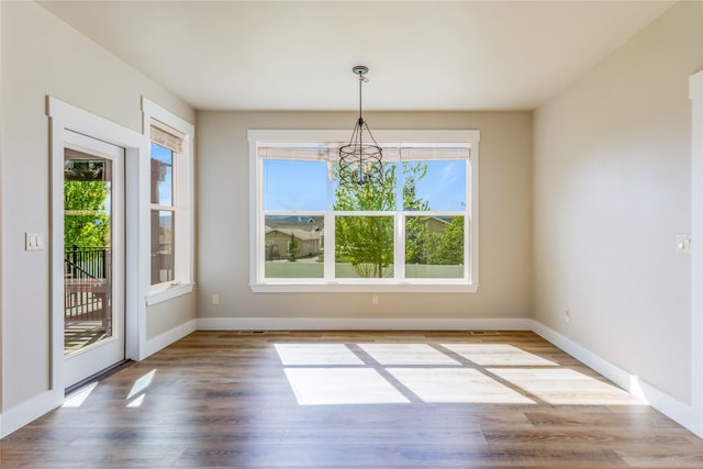 unfurnished dining area featuring a chandelier, plenty of natural light, and baseboards