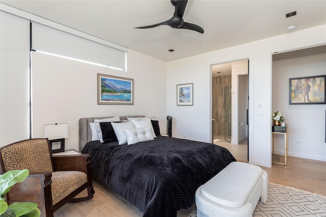 bedroom featuring light wood finished floors, ceiling fan, ensuite bath, and baseboards