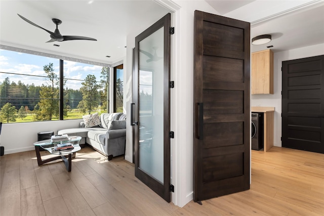 living area with light wood finished floors, a ceiling fan, washer / dryer, and baseboards