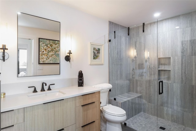 bathroom featuring a shower stall, toilet, and vanity