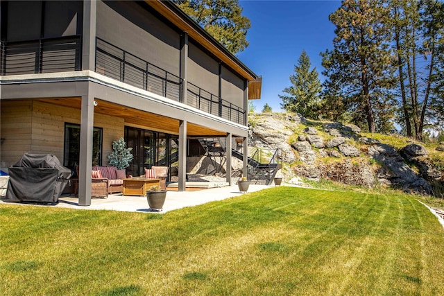 rear view of house featuring an outdoor hangout area, a patio, a yard, and a balcony