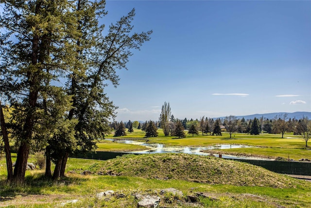 surrounding community with a water and mountain view, golf course view, and a yard