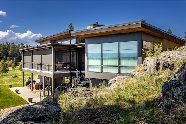 rear view of property featuring a sunroom, a patio area, and stairway