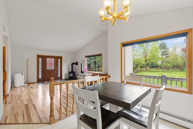 525 Tower St, Missoula, MT 59804 - dining room with a wood stove, a chandelier, vaulted ceiling, light wood-type flooring, and baseboards