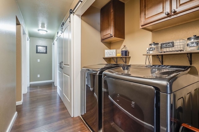 washroom with washer and dryer, dark wood finished floors, baseboards, cabinet space, and a barn door
