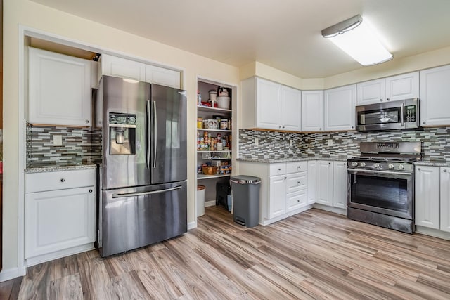 kitchen featuring stainless steel appliances, white cabinetry, and decorative backsplash