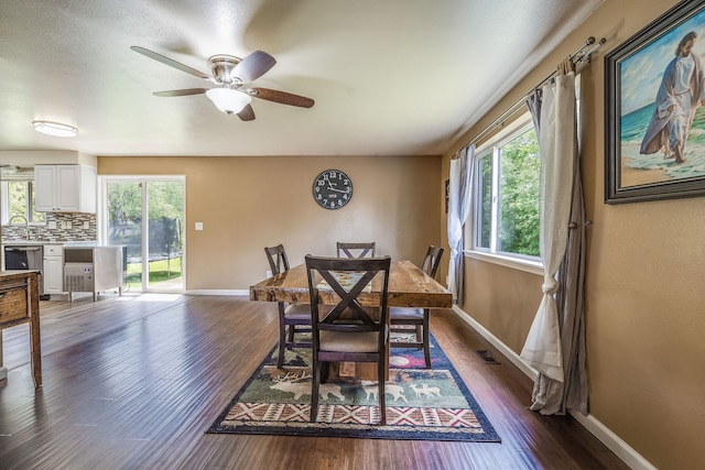 dining space with healthy amount of natural light, dark wood-style floors, baseboards, and ceiling fan