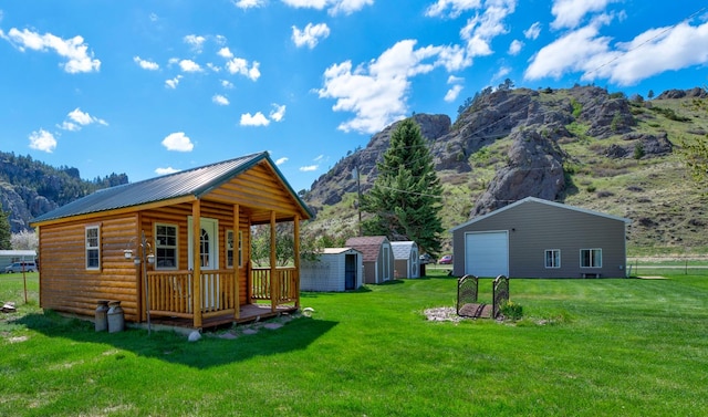 71 Seibold Ln, Cascade, MT 59421 - view of property exterior featuring an outdoor structure, a garage, a mountain view, log veneer siding, and a lawn