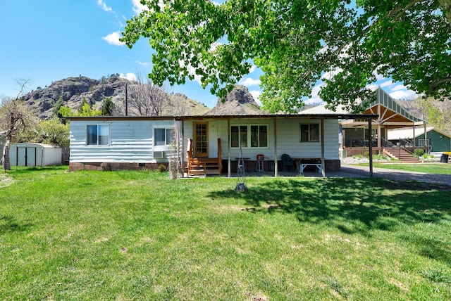 ranch-style house with a shed, a mountain view, a front lawn, and an outdoor structure