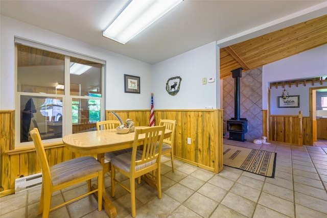 28152 White Swan Ln, Polson, MT 59860 - dining space with healthy amount of natural light, wainscoting, a wood stove, light tile patterned flooring, and wood walls