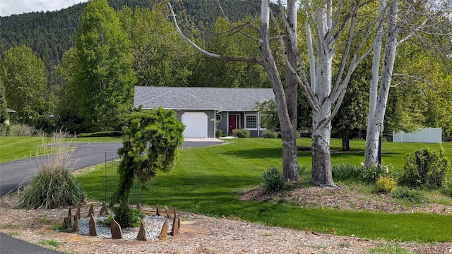 286 Edgewater Dr, Libby, MT 59923 - view of front facade with a garage, roof with shingles, asphalt driveway, a wooded view, and a mountain view