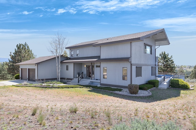 back of house with a porch, a garage, a shingled roof, and driveway