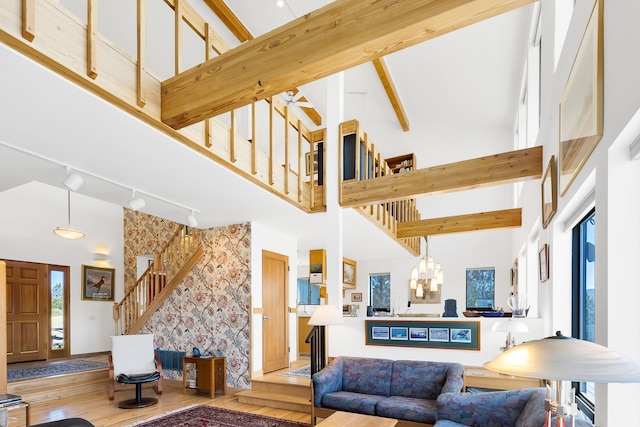 living area with high vaulted ceiling, stairway, wood finished floors, a chandelier, and track lighting