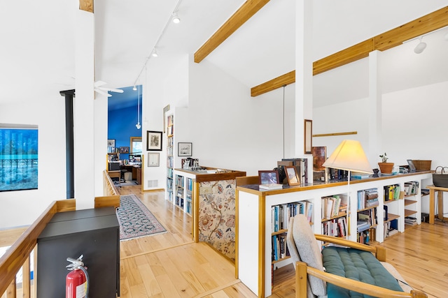 hallway featuring rail lighting, high vaulted ceiling, wood finished floors, and beam ceiling