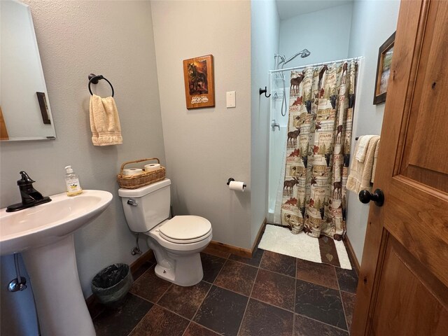26 Castele Ln, Trout Creek, MT 59874 - full bath featuring curtained shower, toilet, baseboards, and stone tile floors