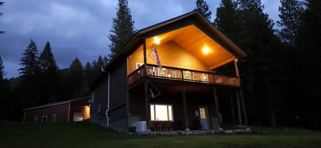 26 Castele Ln, Trout Creek, MT 59874 - back of house at twilight featuring a deck, a lawn, a garage, and a cooling unit