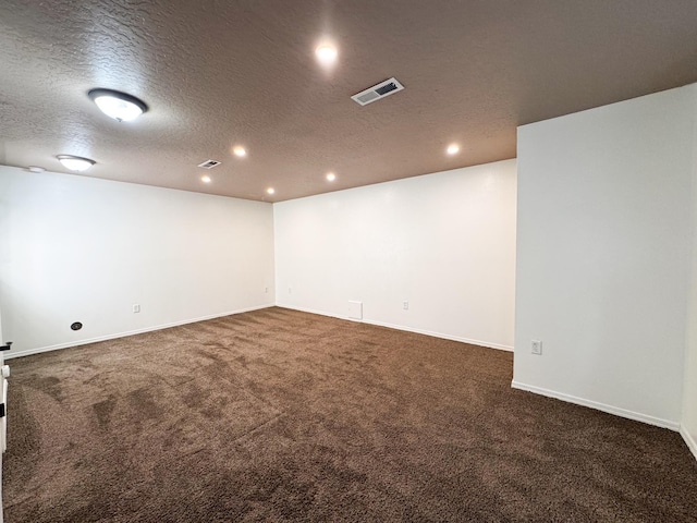 spare room featuring a textured ceiling, recessed lighting, dark colored carpet, and baseboards