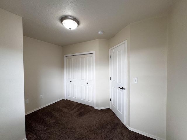unfurnished bedroom featuring carpet, baseboards, a textured ceiling, and a closet