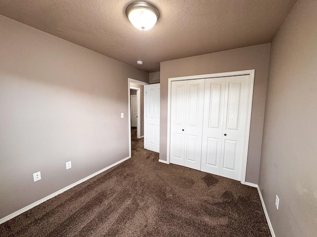 unfurnished bedroom featuring carpet, baseboards, a textured ceiling, and a closet
