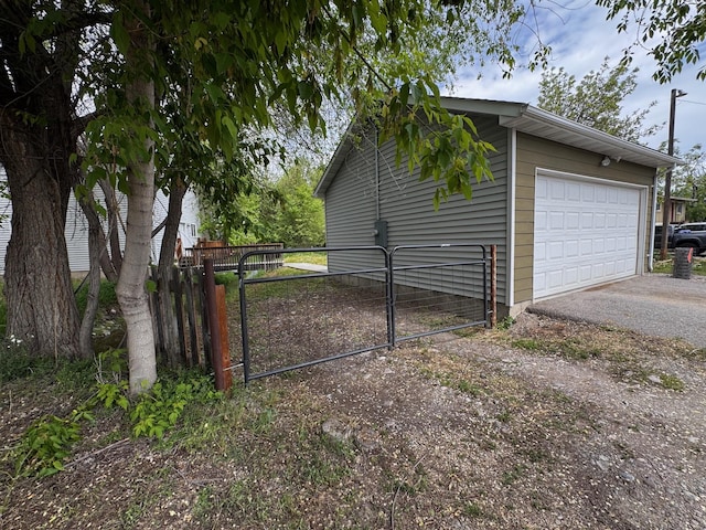 garage featuring a gate, driveway, and fence