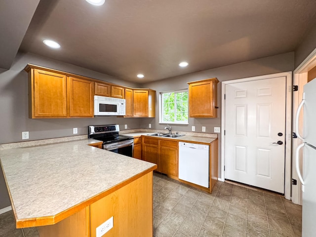 kitchen featuring white appliances, a peninsula, light countertops, a sink, and recessed lighting
