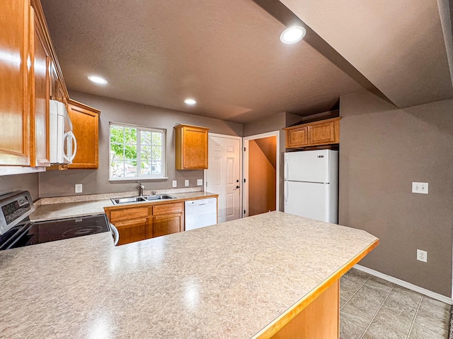 kitchen featuring white appliances, a peninsula, a sink, light countertops, and recessed lighting