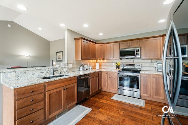 kitchen with stainless steel appliances, a sink, a peninsula, dark wood-style floors, and light stone countertops