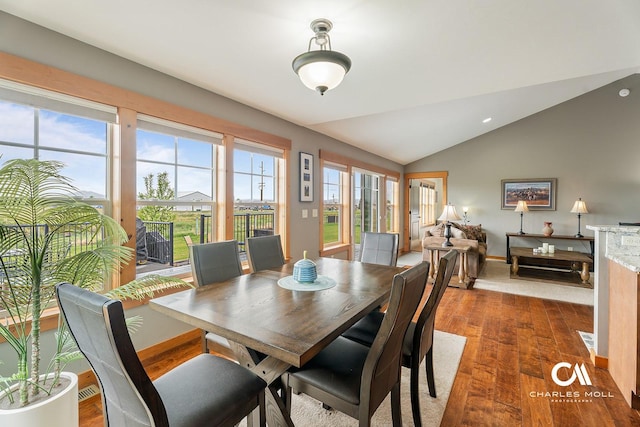 dining space featuring dark wood-style floors, lofted ceiling, and baseboards