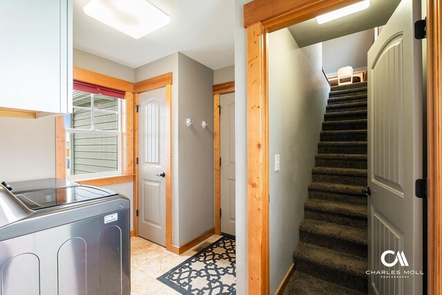 laundry area with washer and clothes dryer, cabinet space, light tile patterned floors, and baseboards