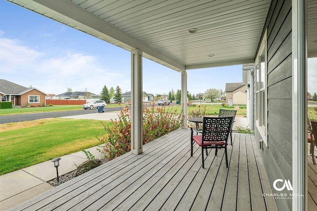 wooden terrace featuring a porch, a lawn, and a residential view