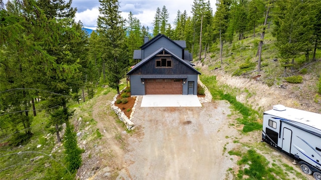 25 Hodge Rdg, Kila, MT 59920 - view of front of home with a chimney, a wooded view, a garage, and dirt driveway