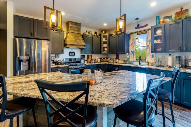 25 Hodge Rdg, Kila, MT 59920 - kitchen featuring appliances with stainless steel finishes, custom exhaust hood, a sink, decorative light fixtures, and glass insert cabinets