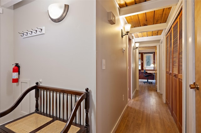 hallway featuring wood finished floors, baseboards, and wooden ceiling