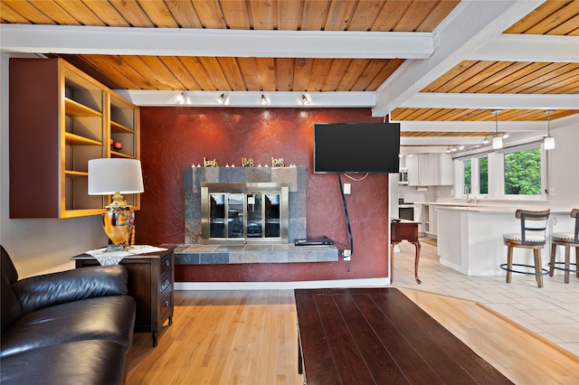 living room with a fireplace, wood ceiling, beam ceiling, and light wood-style flooring
