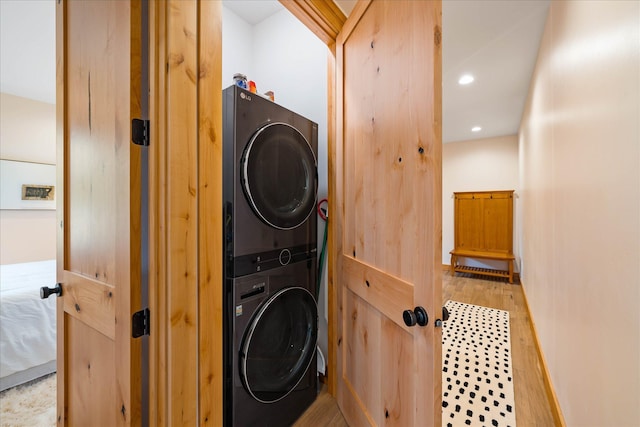 clothes washing area featuring stacked washer / dryer, wood finished floors, recessed lighting, and baseboards