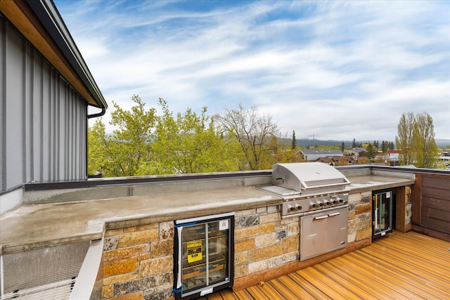 wooden terrace featuring beverage cooler, area for grilling, and an outdoor kitchen