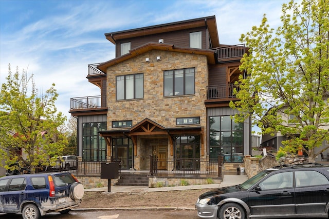 contemporary home featuring stone siding, a balcony, and a porch